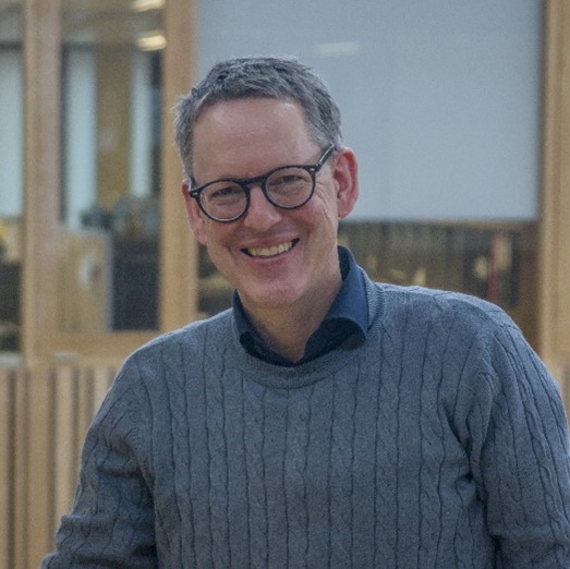 A portrait of a man with glasses looking towards the camera